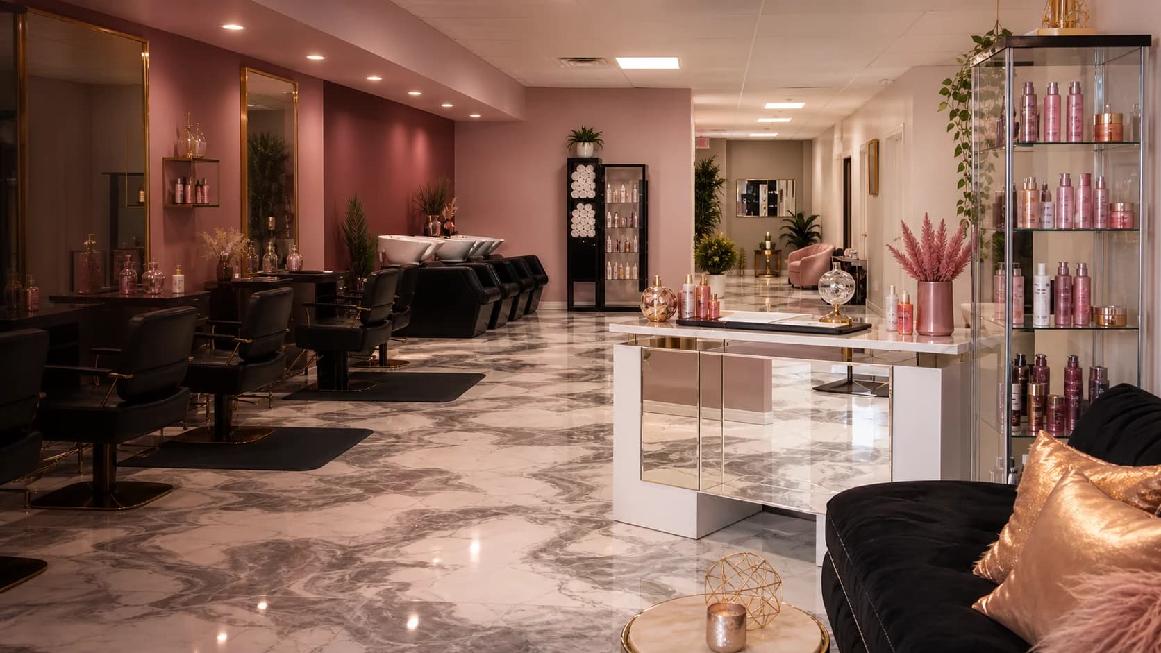 Warm modern salon interior with marble floors, black styling chairs, blush accents, and gold details